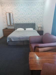 阿克套维多利亚酒店的一间卧室配有一张床、一张沙发和一面镜子