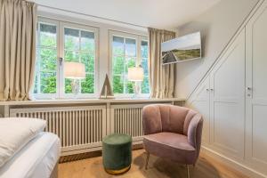 凯图姆Inselliebe Exklusive Sylter Wellnessoase mit Sauna Garten in Keitum的一间卧室配有一张床、一把椅子和窗户。