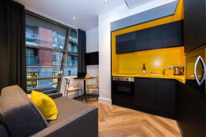 都柏林Staycity Aparthotels Dublin Castle的带沙发的客厅和黄色的厨房