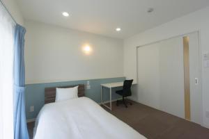 宫古岛BiBi Hotel 宮古空港前 SouthTower的一间卧室配有一张大床和一张书桌