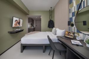 马尼拉The Suites at Torre Lorenzo Malate - Managed by The Ascott Limited的酒店客房带一张床、一张书桌和一面镜子