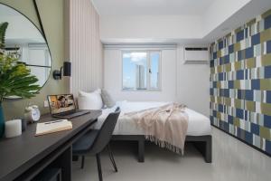 马尼拉The Suites at Torre Lorenzo Malate - Managed by The Ascott Limited的一间卧室配有一张床和一张带笔记本电脑的书桌