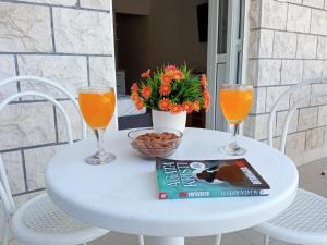 KomolacSun Studio Apartment的一张带两杯橙汁和一本书的白色桌子