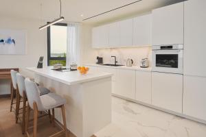 萨武德里亚Petram Resort & Residences的白色的厨房配有白色橱柜和酒吧凳子