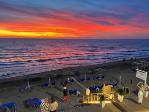 阿齐欧斯·贡多斯Romantic Palace Beach Apartments的一群人,在日落时站在海滩上