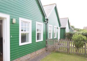 巴姆博格No 9 Armstrong Cottage的绿色房子,设有白色窗户和围栏