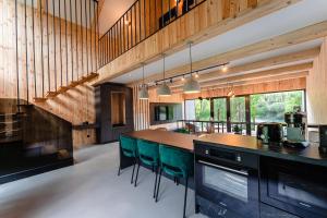 TeşilaVila ZIA的厨房设有木墙和带绿色椅子的柜台。