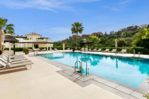 奥亨Luxury & Sunny Apartment with Breathtaking View in Marbella East的一个带躺椅的大型游泳池,棕榈树