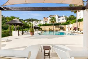 奥亨Luxury & Sunny Apartment with Breathtaking View in Marbella East的享有带椅子和桌子的游泳池的景色