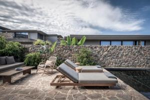加藤-达拉特索Domes Zeen Chania, a Luxury Collection Resort, Crete的一个带沙发和椅子的庭院和石墙
