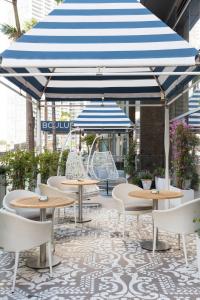 迈阿密迈阿密布杂艺术酒店的庭院配有桌椅和蓝白雨伞。