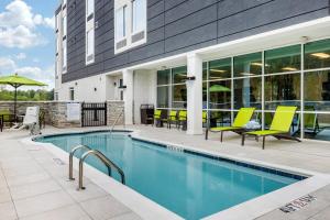 夏洛特SpringHill Suites Charlotte Southwest的一座游泳池,旁边是一座黄椅