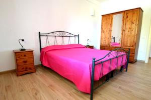 新福卡Villetta 6 posti vicino spiaggia的卧室设有粉红色的床和木地板