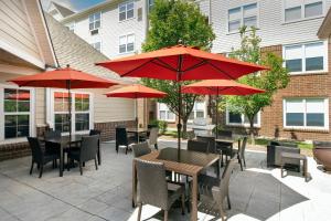 森特尼尔丹佛南/帕克迈德斯购物中心原住客栈的一个带桌椅和红伞的庭院