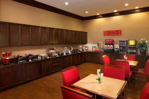 休斯顿休斯顿洲际机场万豪广场套房酒店的一间带桌子和红色椅子的餐厅和一间厨房