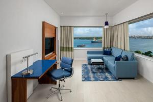 达累斯萨拉姆Four Points by Sheraton Dar es Salaam New Africa的客厅配有蓝色的沙发、桌子和椅子