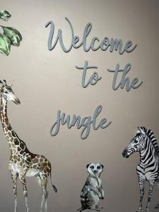 赫尔Cottage/boutique style - Free parking & Wi-Fi的表示欢迎长颈鹿和斑马进入丛林的标志