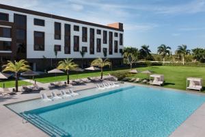 蓬塔卡纳AC Hotel by Marriott Punta Cana的一张酒店图,里面设有游泳池和椅子