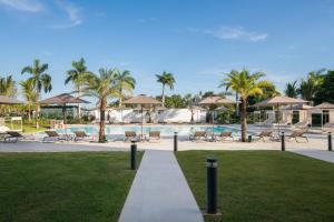 蓬塔卡纳AC Hotel by Marriott Punta Cana的度假村内带椅子和遮阳伞的游泳池