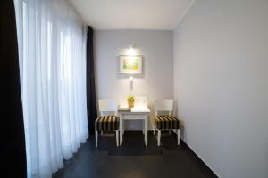 米泽德沃兹Hotel Amber Suite Enklawa dla Dorosłych的配有桌子、两把椅子和窗帘的房间