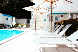 阿尔塔维拉米利恰Principe Alogna Hotel & SPA的游泳池旁的一排白色椅子和遮阳伞