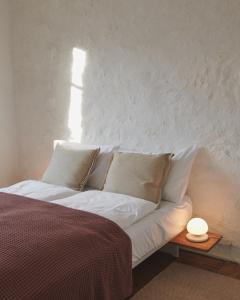 波朗特吕奥伯格穆登旅馆的一张带白色枕头的床和一张桌子上的台灯