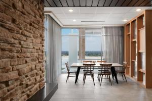 新奥尔巴尼Fairfield Inn & Suites Louisville New Albany IN的一间设有桌椅和砖墙的用餐室