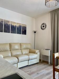 平佐洛Pinzolo DOLOMIA apartment的客厅配有沙发和墙上的时钟
