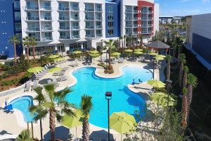 奥兰治比奇SpringHill Suites Orange Beach at The Wharf的享有带遮阳伞的度假村游泳池的空中景致