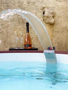 阿尔盖罗Villa Boeddu, relax tra mare e campagna的在游泳池里一瓶葡萄酒和两杯酒