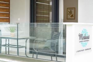 尼亚普拉莫斯Medusa Luxury Apartments的一个带桌子和椅子的玻璃阳台