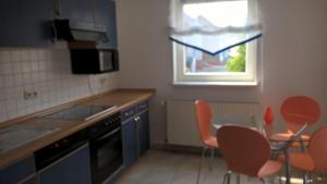 伊尔梅瑙Wohnung Nähe Uni Ilmenau und Autobahn A71的厨房配有橙色椅子、桌子和窗户