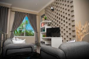 姆万扎Hotel Kingdom Appartments的客厅配有两把椅子和电视