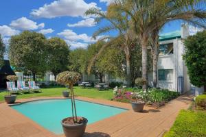 波罗瓜尼波罗克瓦尼地标万豪Protea酒店的一座棕榈树游泳池和一座房子