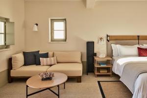 纳乌萨考斯米提斯酒店的一间卧室配有一张床、一张沙发和一张桌子