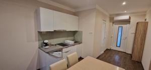 哈卡尼Azra Apartman的厨房配有白色橱柜和桌椅