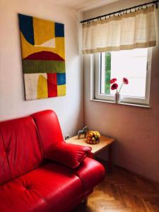 普罗马尼亚M5的一张红色的沙发,位于一个配有桌子和窗户的房间