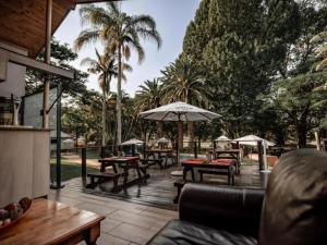白河Hotel 247 @ White River的一个带桌子和遮阳伞及棕榈树的庭院