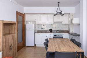 埃斯塔蒂特RVHotels Apartamentos La Pineda的厨房配有白色橱柜和木桌