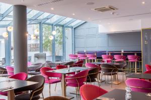 萨尔布吕肯Premier Inn Saarbrücken City Centre的用餐室配有桌子和粉红色的椅子