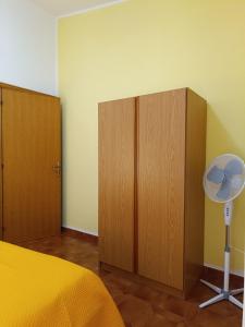 卡拉古诺内Piccolo Hotel Nuova gestione的一间卧室配有一张床、木制橱柜和风扇。