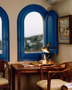 卡夫里尔斯Hostal de la Plaça - Hotel Boutique的蓝色的客房设有桌子和2个窗户