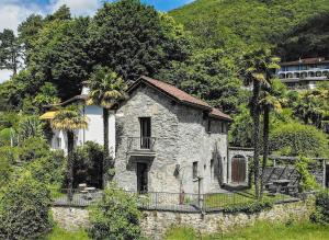 洛迦诺Palm Cottage的一座古老的石头房子,山坡上种有棕榈树