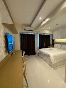 马尼拉Coast Residences Penthouse with skyline and manila bay view的一间卧室配有一张床和一张书桌及电视