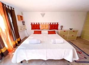 奥里斯塔诺Hibryd: in centro, a due passi dal mare的卧室配有带橙色枕头的大型白色床