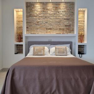 Bisaccia多莫斯洛穆列亚酒店的一间卧室设有一张带砖墙的大床