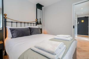 伦敦The Balham Hideaway的卧室配有白色床和毛巾