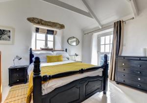 森嫩The Byre - Sennen的一间卧室设有黑色和黄色的床和窗户。