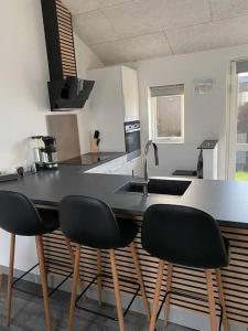 斯卡恩Fin ny moderniseret lejlighed i Skagen.的厨房配有3把黑色椅子和台面
