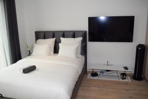卢森堡LAWSON'S GOLD BELL STUDIO的卧室配有带白色床单的床铺和平面电视。